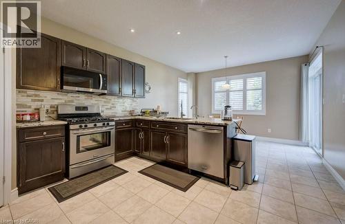 Kitchen featuring wood cabinetry, stainless steel appliances, granite countertops, and a tiled backsplash - 331 Westpark Crescent Unit# Upper, Waterloo, ON - Indoor Photo Showing Kitchen