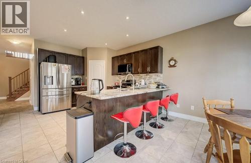 Kitchen featuring dark wood cabinetry, stainless steel appliances, a tile backsplash, and a breakfast bar with a light-toned countertop - 331 Westpark Crescent Unit# Upper, Waterloo, ON - Indoor