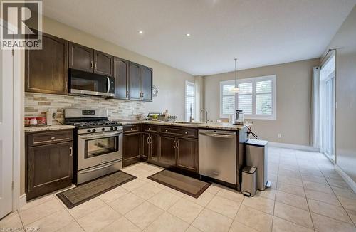 Kitchen featuring dark wood cabinetry, stainless steel appliances, and light-toned tile flooring - 331 Westpark Crescent Unit# Upper, Waterloo, ON - Indoor Photo Showing Kitchen