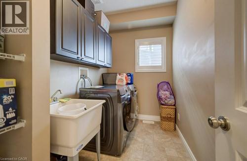 Dedicated laundry room featuring dark wood-finish cabinetry, a utility sink with faucet, and tile flooring - 331 Westpark Crescent Unit# Upper, Waterloo, ON - Indoor Photo Showing Laundry Room