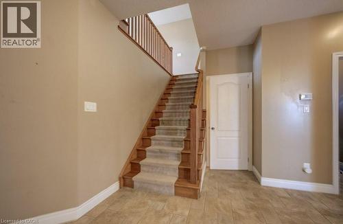 Staircase featuring wood railing and carpeted treads, with tile flooring and a white paneled door - 331 Westpark Crescent Unit# Upper, Waterloo, ON - Indoor Photo Showing Other Room