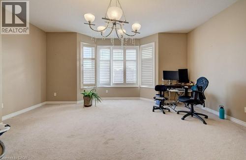 Spacious room featuring a bay window with plantation shutters, neutral carpeting, and a decorative ceiling chandelier - 331 Westpark Crescent Unit# Upper, Waterloo, ON - Indoor