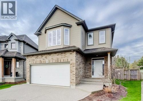 Two-story residence featuring a brick and siding exterior, an attached garage, a front entry with a covered porch, multiple windows with white shutters, and a concrete driveway - 331 Westpark Crescent Unit# Upper, Waterloo, ON - Outdoor With Facade