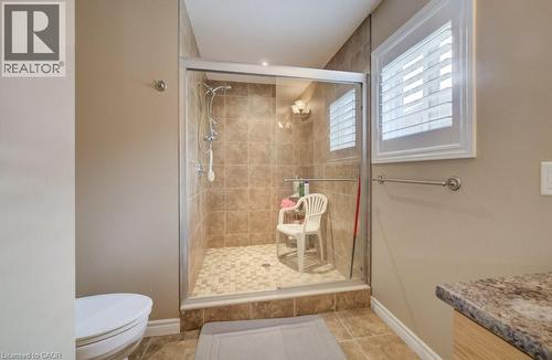 Glass-enclosed shower with a tiled surround, mosaic-tiled floor, and a built-in window with white plantation shutters - 331 Westpark Crescent Unit# Upper, Waterloo, ON - Indoor Photo Showing Bathroom