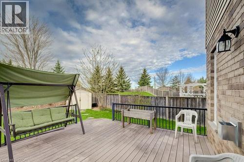 Expansive wood-finish deck with black metal railings, a manicured lawn, and a light brick exterior featuring an attached exterior light fixture - 331 Westpark Crescent Unit# Upper, Waterloo, ON - Outdoor With Exterior