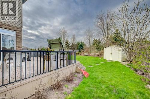 Exterior deck with black metal railing, offering access to a manicured lawn featuring a storage shed and mature landscaping - 331 Westpark Crescent Unit# Upper, Waterloo, ON - Outdoor