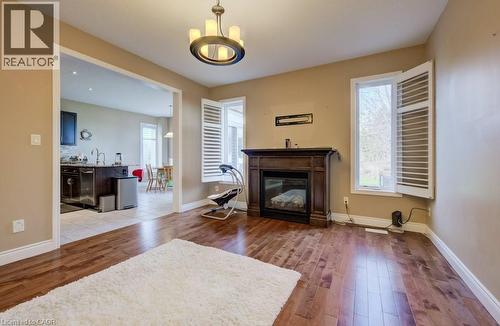 Living area featuring wood-finish flooring, a dark wood mantel with an electric fireplace, a bronze chandelier, and window shutters - 331 Westpark Crescent Unit# Upper, Waterloo, ON - Indoor Photo Showing Living Room With Fireplace