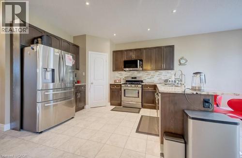 Kitchen featuring stainless steel appliances, dark wood-finish cabinetry, light-toned tiled flooring, and recessed lighting - 331 Westpark Crescent Unit# Upper, Waterloo, ON - Indoor Photo Showing Kitchen