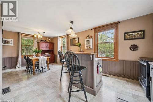 Kitchen and dining area featuring wood-finish flooring, a built-in breakfast bar, and multiple windows with wood trim - 630 Robert Ferrie Drive, Kitchener, ON - Indoor Photo Showing Dining Room