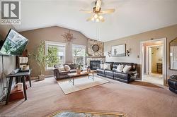Living room featuring a vaulted ceiling and a stone-faced fireplace with a mantel - 