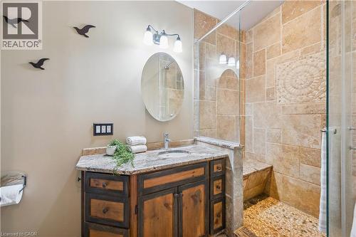Bathroom featuring a custom wood vanity with a granite countertop, undermount sink, and a framed oval mirror - 630 Robert Ferrie Drive, Kitchener, ON - Indoor Photo Showing Bathroom