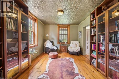 Room featuring a pressed tin ceiling, wood-finish flooring, and built-in shelving with glass-front doors - 630 Robert Ferrie Drive, Kitchener, ON - Indoor