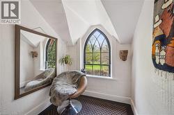 Arched window with black framing overlooking mature trees and green space - 