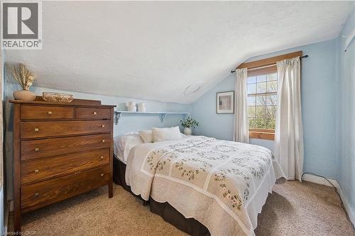 Carpeted room featuring a window with wood trim, sloped ceiling, and light blue walls - 630 Robert Ferrie Drive, Kitchener, ON - Indoor Photo Showing Bedroom