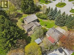 Expansive lot featuring a primary residence with a multi-level deck, a secondary structure with a red roof, and established trees providing natural screening - 