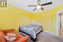 Bright bedroom featuring yellow walls and grey carpeting - 