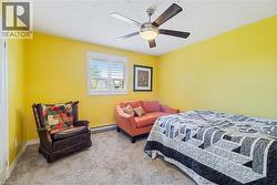 Room featuring textured carpeting, a window with white plantation shutters, and a ceiling fan with integrated lighting - 