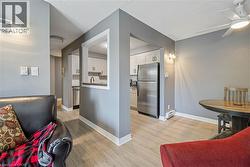 Light wood-finish flooring extends throughout the living area, featuring a ceiling fan with integrated lighting - 