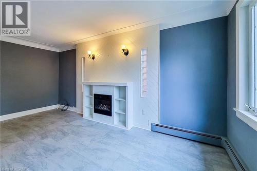 Unfurnished living/dining room with a fireplace, built in shelves, and a baseboard radiator. - 156 Park Row S, Hamilton, ON - Indoor With Fireplace