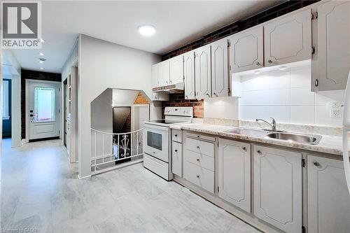 Kitchen with electric range, light countertops, white cabinetry, under cabinet range hood, and backsplash - 156 Park Row S, Hamilton, ON - Indoor Photo Showing Kitchen With Double Sink