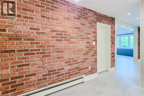 Hall featuring baseboard heating, brick wall, recessed lighting, and a baseboard heating unit - 156 Park Row S, Hamilton, ON - Indoor Photo Showing Other Room