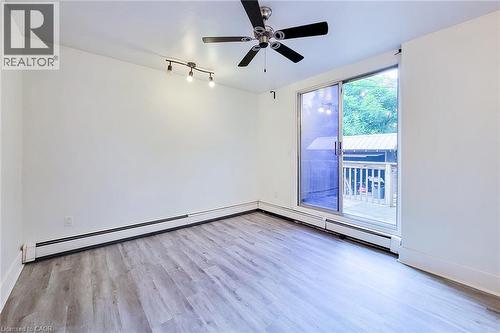 Unfurnished bedroom featuring wood finished floors, a baseboard heating unit, track lighting, a ceiling fan and sliding doors out to the back deck. - 156 Park Row S, Hamilton, ON - Indoor Photo Showing Other Room