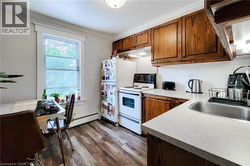 Kitchen featuring white range with electric stovetop, decorative backsplash, crown molding, dark wood finished floors, and under cabinet range hood. - 156 Park Row S, Hamilton, ON - Indoor Photo Showing Kitchen
