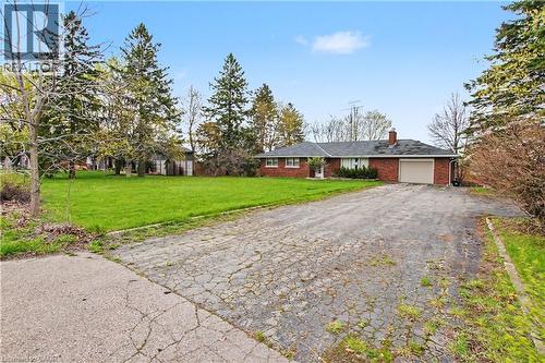 Brick ranch home featuring a single garage, dark shingle roof, and a prominent chimney - 355 Guelph Avenue, Cambridge, ON 