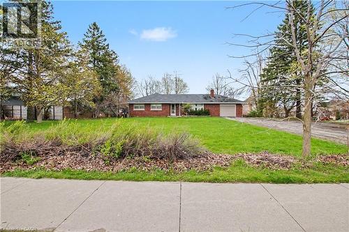 Brick ranch-style residence featuring an attached garage, a paved driveway, and a spacious front lawn - 355 Guelph Avenue, Cambridge, ON 