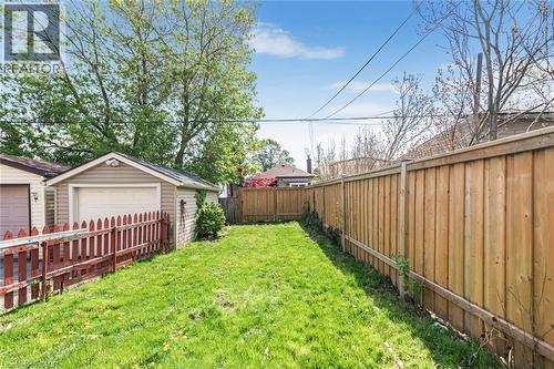 Expansive grassy yard area featuring a detached garage with vinyl siding and an overhead door - 114 Weir Street N, Hamilton, ON - Outdoor