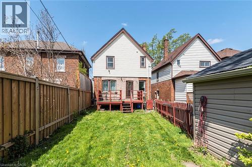 Expansive backyard featuring a green lawn, wooden privacy fencing, and a multi-level deck with access to the residence - 114 Weir Street N, Hamilton, ON - Outdoor With Deck Patio Veranda With Exterior