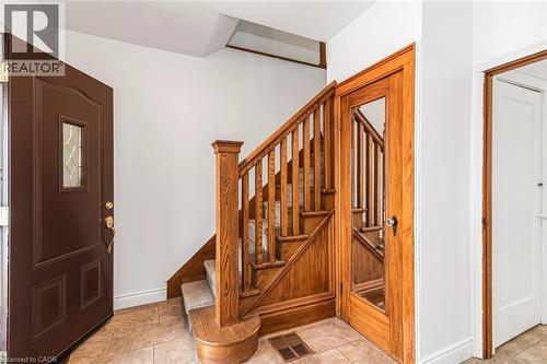 Foyer featuring a wood staircase with carpeted treads, a solid wood entry door with leaded glass insert, a wood-framed door with a full-length glass panel, and light-toned tile flooring - 114 Weir Street N, Hamilton, ON - Indoor Photo Showing Other Room