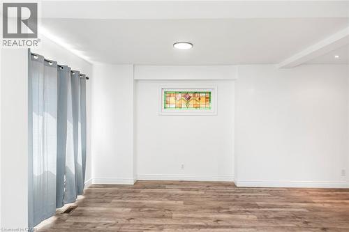 Dining area featuring a modern black pendant light fixture, wood-finish flooring, and a unique stained-glass window - 114 Weir Street N, Hamilton, ON - Indoor Photo Showing Other Room