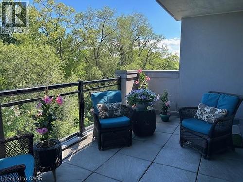 Outdoor patio space with stone tile flooring, a glass and metal railing, and a privacy wall - 34 Plains Road E Unit# 408, Burlington, ON - Outdoor With Exterior
