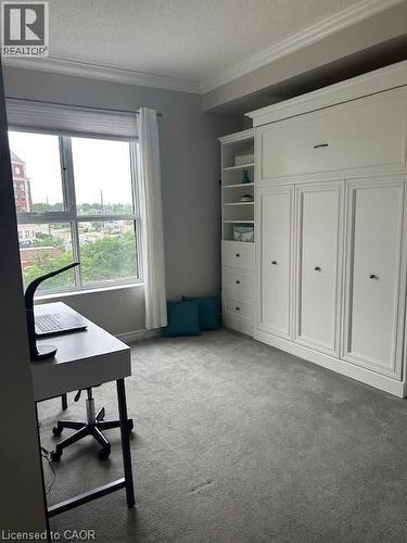 Built-in wall unit with storage and display shelving, accompanied by a large window and grey carpeting - 34 Plains Road E Unit# 408, Burlington, ON - Indoor