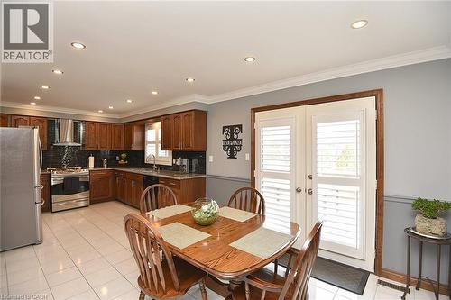 Kitchen featuring wood cabinetry, stainless steel appliances, granite countertops, and dark tile backsplash - 36 Tommar Place, Hamilton, ON - Indoor Photo Showing Dining Room