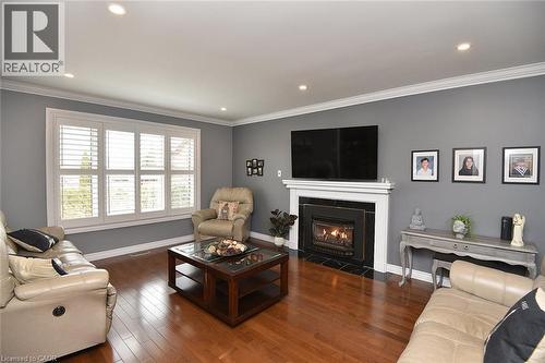 Living area featuring wood-finish flooring, a white mantel fireplace with a dark surround, and recessed lighting - 36 Tommar Place, Hamilton, ON - Indoor Photo Showing Living Room With Fireplace
