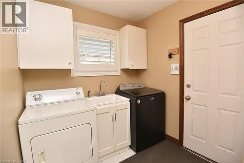 Dedicated laundry area featuring a utility sink with chrome faucet, white cabinetry, and a window with louvered shutters - 36 Tommar Place, Hamilton, ON - Indoor Photo Showing Laundry Room