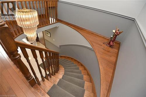 Curved hardwood staircase featuring a gray runner, wood balusters, and a tiered glass chandelier - 36 Tommar Place, Hamilton, ON - Indoor Photo Showing Other Room