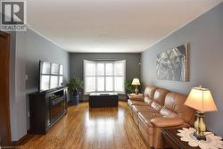 Hardwood flooring throughout featuring a bay window with plantation shutters - 