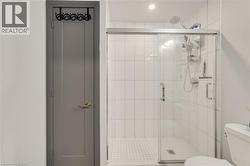 Modern shower enclosure featuring a clear glass sliding door, white subway tile walls, and a white mosaic tile shower pan - 