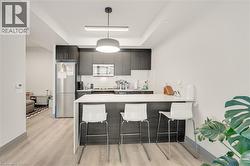 Modern kitchen featuring dark cabinetry, stainless steel appliances, and a white countertop island with seating - 