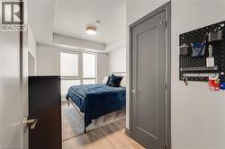 Room featuring light wood-finish flooring, white walls, and a large window with horizontal blinds - 