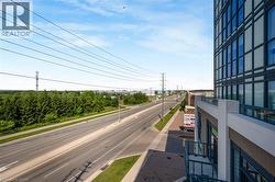 Expansive urban landscape with a wide paved road, surrounding evergreen trees, and modern building architecture - 