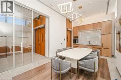 Contemporary kitchen area featuring wood-finish cabinetry, a stone backsplash, integrated stainless steel appliances, and a matte black faucet - 