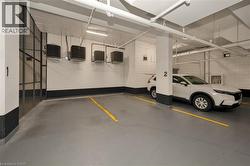 Secure indoor parking space featuring painted concrete flooring, overhead fluorescent lighting, and visible utility conduits - 