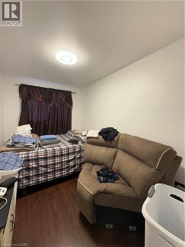 Room featuring wood-finish flooring, a window with dark drapes, white walls, and a flush-mount ceiling light fixture - 181 Thaler Avenue, Kitchener, ON 