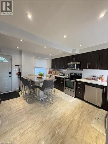 Kitchen featuring wood-finish cabinetry, stainless steel appliances, a center island with seating, recessed lighting, and large format tile flooring - 181 Thaler Avenue, Kitchener, ON 