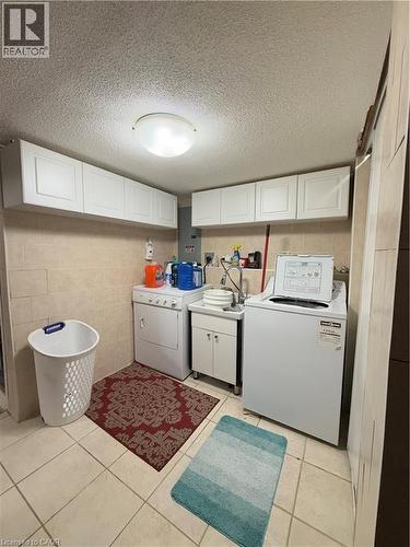 Dedicated utility room featuring tile flooring, a utility sink with cabinet storage, and extensive upper cabinetry - 181 Thaler Avenue, Kitchener, ON 
