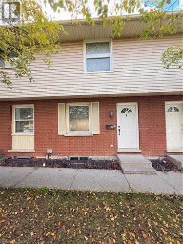 Brick and siding exterior featuring a white entry door with an arched window, a wall-mounted light fixture, and concrete steps - 181 Thaler Avenue, Kitchener, ON 